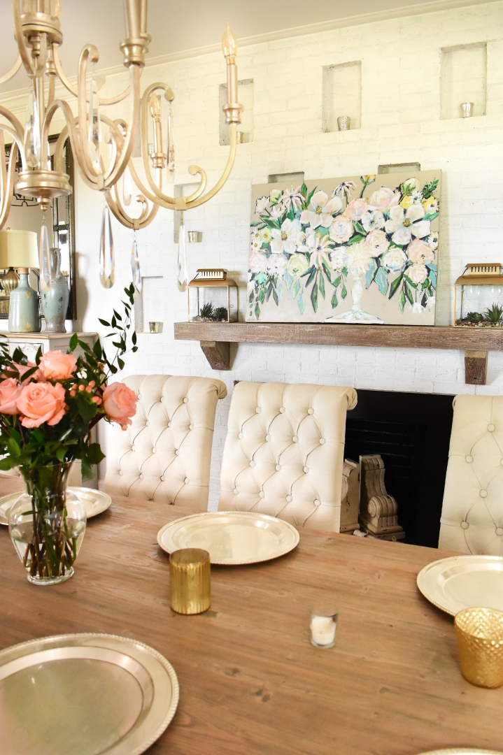 neutral dining room with gold chandelier and floral painting